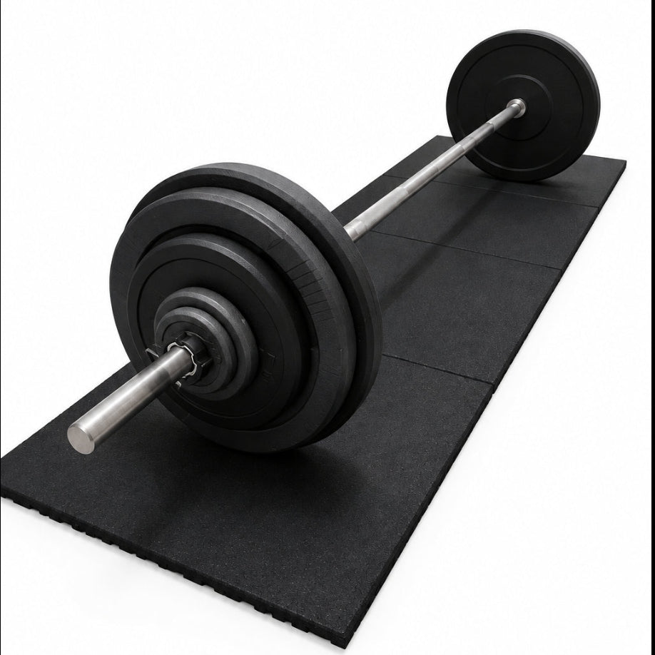 A barbell with black weight plates resting on a black rubber gym mat