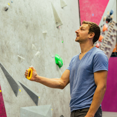 Man pinching on rubber rings for climbing warm up tools